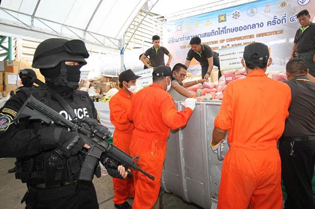 Armed police watch as anti-narcotics officials handle tonnes of methamphetamine pills in bins, readying the drugs for incineration, at Bang Pa-in Industrial Estate in Bang Pa-in district, Ayutthaya, on Friday. (Photo by Sunthorn Pongpao)